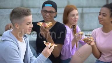 一群心情愉快的青少年在披萨午餐时真诚地笑，友谊